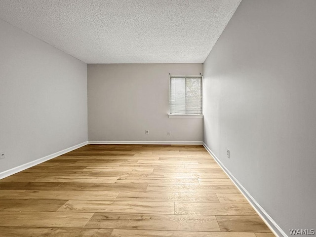 spare room with a textured ceiling and light hardwood / wood-style floors