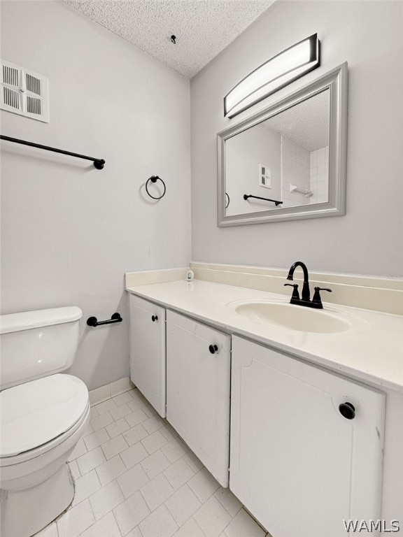 bathroom featuring toilet, vanity, tile patterned floors, and a textured ceiling