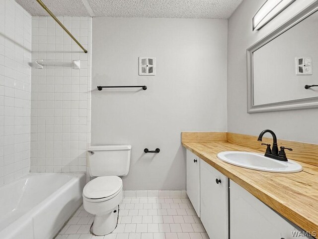 full bathroom featuring toilet, vanity, tile patterned flooring, and a textured ceiling