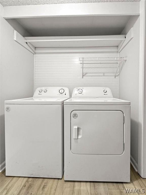 laundry room featuring washing machine and clothes dryer and hardwood / wood-style flooring