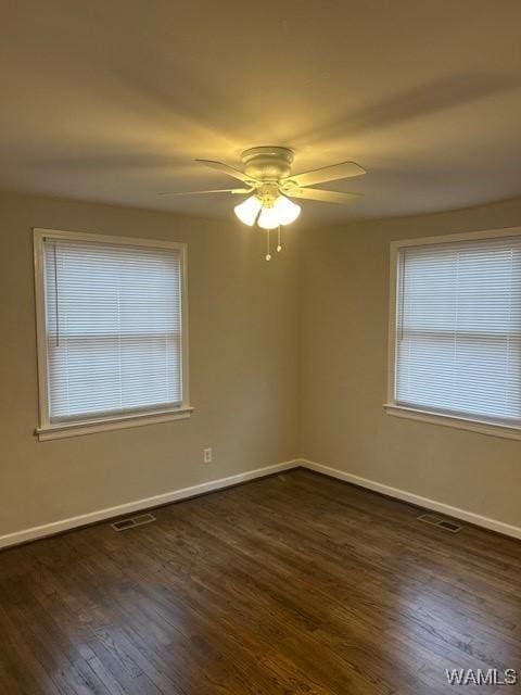 spare room featuring ceiling fan, baseboards, visible vents, and dark wood finished floors