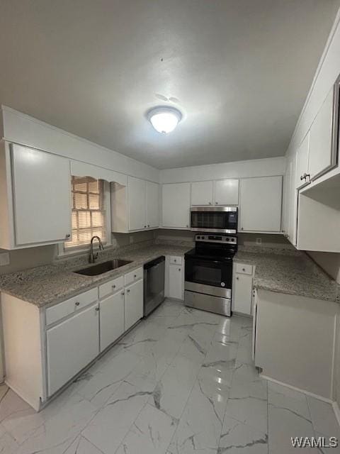 kitchen with appliances with stainless steel finishes, marble finish floor, white cabinets, and a sink