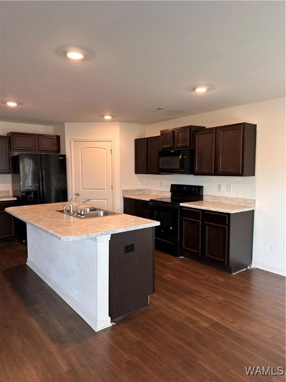 kitchen with black appliances, a center island with sink, sink, dark hardwood / wood-style floors, and dark brown cabinets