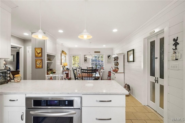 kitchen featuring crown molding, white cabinetry, stainless steel oven, and pendant lighting