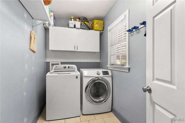 clothes washing area featuring cabinets, washing machine and dryer, and light tile patterned flooring