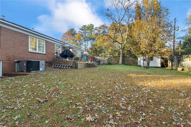 view of yard with a wooden deck, a shed, and central AC