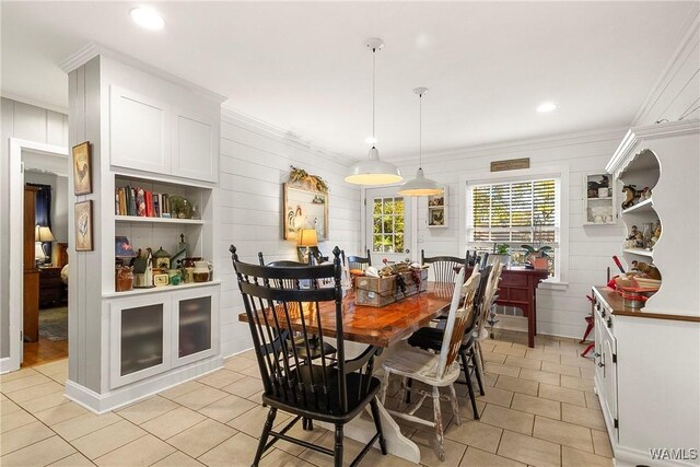 dining area with ornamental molding and wood walls