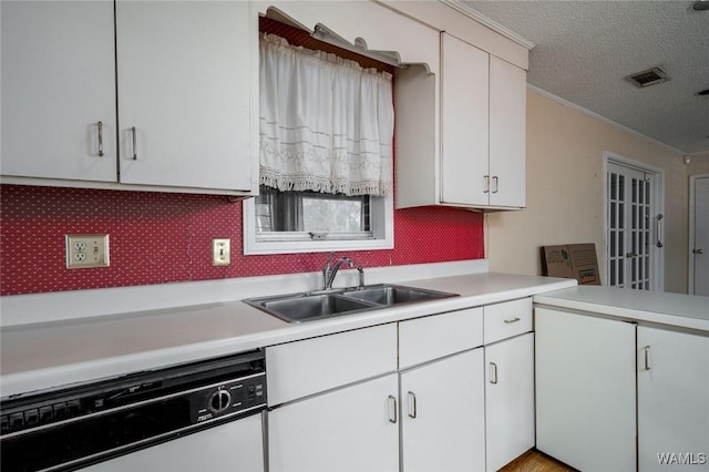 kitchen with sink, dishwasher, white cabinetry, backsplash, and a textured ceiling