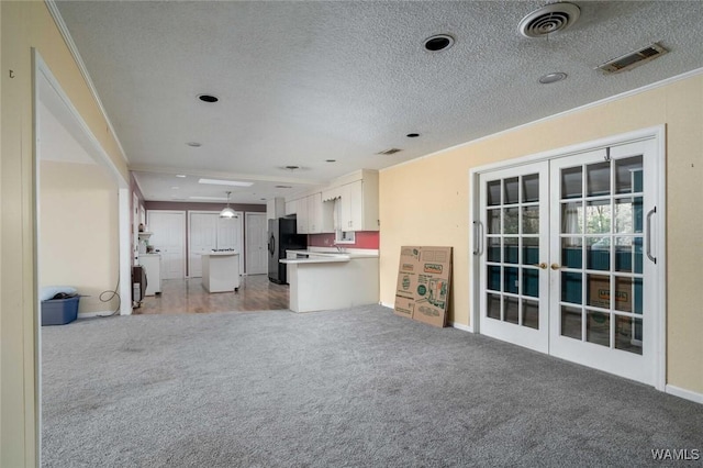 interior space featuring hanging light fixtures, white cabinets, black fridge, light colored carpet, and french doors