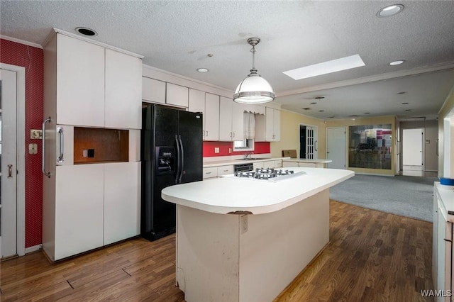 kitchen featuring black fridge with ice dispenser, white cabinetry, white gas stovetop, a kitchen island, and pendant lighting