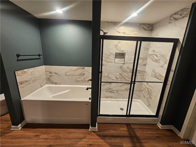 bathroom featuring a bath, a shower stall, wood finished floors, and baseboards