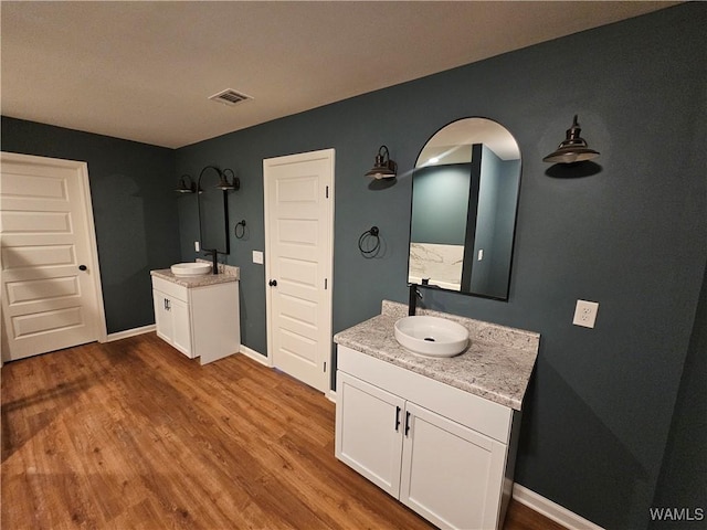 bathroom with two vanities, visible vents, a sink, and wood finished floors