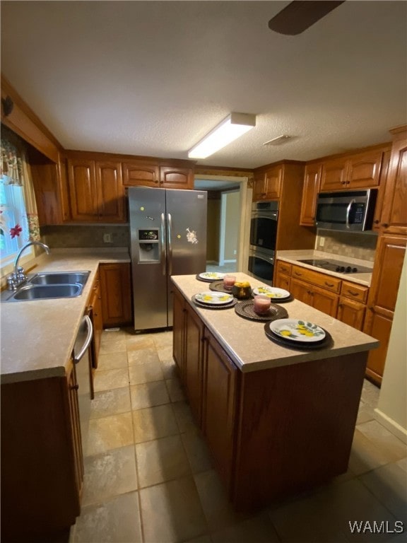 924 12th St SW, Fayette, AL 35555 - kitchen featuring stainless steel appliances, a sink, a kitchen island, light countertops, and brown cabinetry