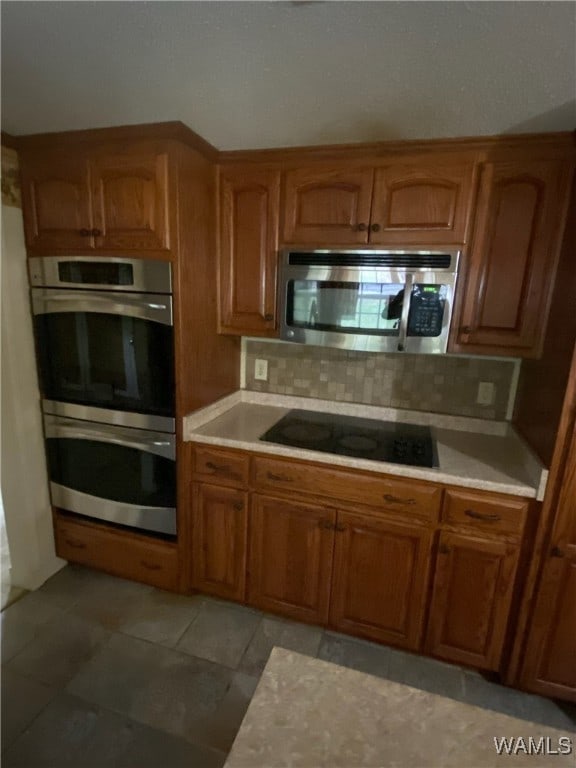 924 12th St SW, Fayette, AL 35555 - kitchen with appliances with stainless steel finishes, light countertops, brown cabinets, and tasteful backsplash