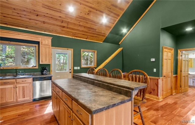 kitchen featuring dishwasher, a center island, sink, light wood-type flooring, and a breakfast bar area