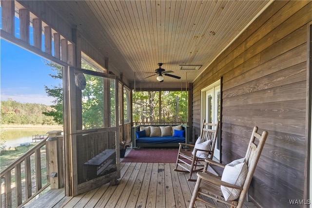 deck with covered porch, a water view, and ceiling fan