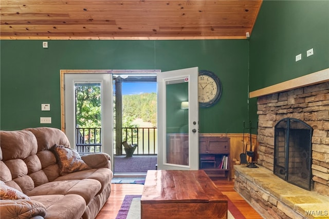 living room featuring a stone fireplace, wooden ceiling, and wood-type flooring