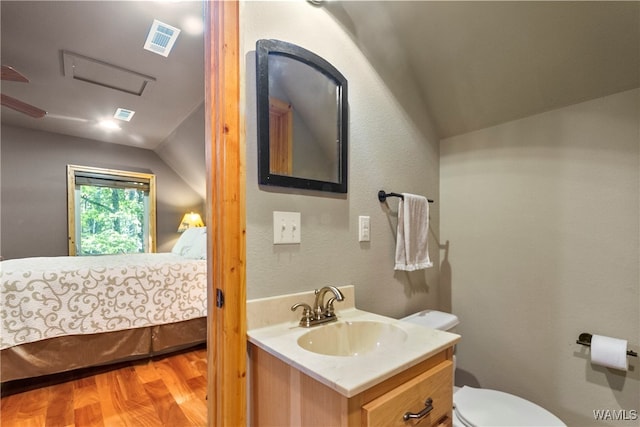 bathroom with toilet, hardwood / wood-style floors, vanity, and vaulted ceiling