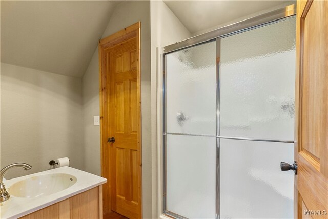 bathroom featuring a shower with shower door, lofted ceiling, and vanity