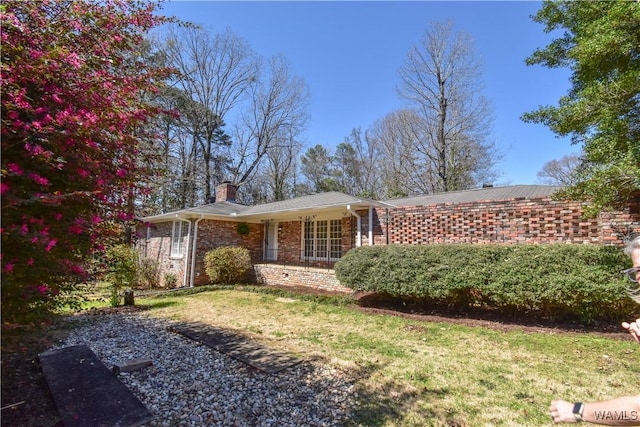 view of front of property featuring brick siding, a front lawn, and a chimney