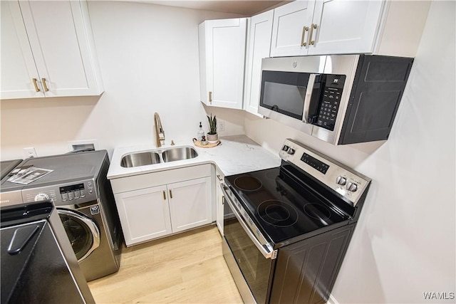 kitchen with white cabinetry, washer / clothes dryer, appliances with stainless steel finishes, and a sink