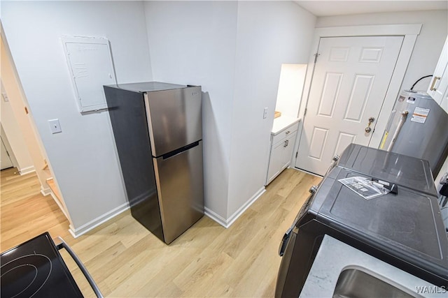 interior space featuring black electric range, light wood-type flooring, baseboards, and freestanding refrigerator