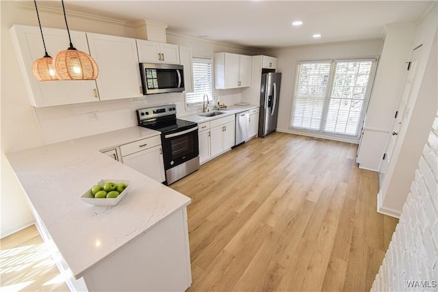 kitchen with a sink, stainless steel appliances, white cabinets, and light wood finished floors