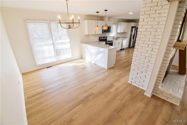 kitchen featuring light countertops, light wood-style floors, white cabinets, stainless steel appliances, and a sink