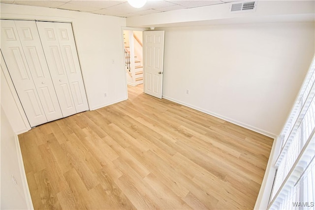 unfurnished bedroom with visible vents, light wood-style flooring, baseboards, and a drop ceiling