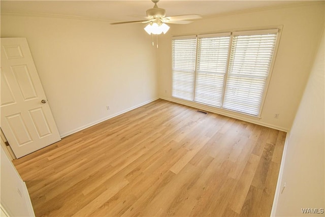 spare room featuring light wood finished floors, baseboards, visible vents, and a wealth of natural light