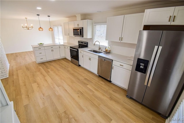 kitchen with light wood-type flooring, appliances with stainless steel finishes, a peninsula, white cabinets, and a sink