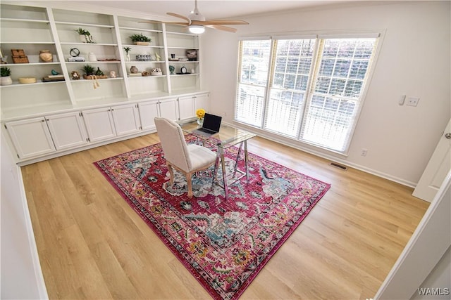 home office featuring visible vents, baseboards, a ceiling fan, and light wood finished floors