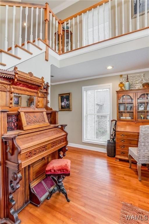 sitting room featuring crown molding, a towering ceiling, baseboards, and wood finished floors