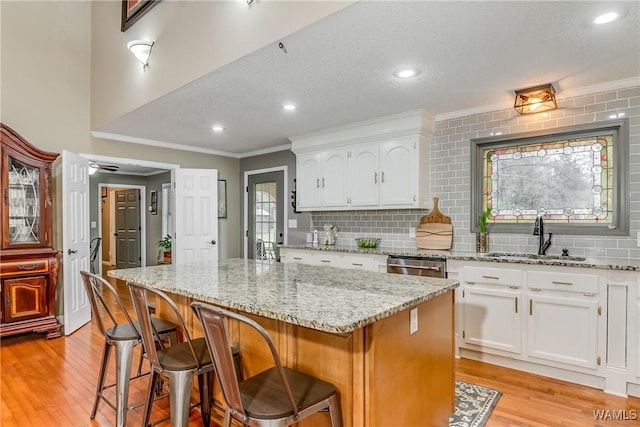 kitchen with white cabinetry, a sink, light wood-style flooring, and dishwasher