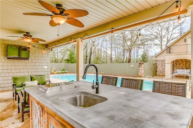 view of patio featuring ceiling fan, a fenced backyard, a sink, and a fenced in pool