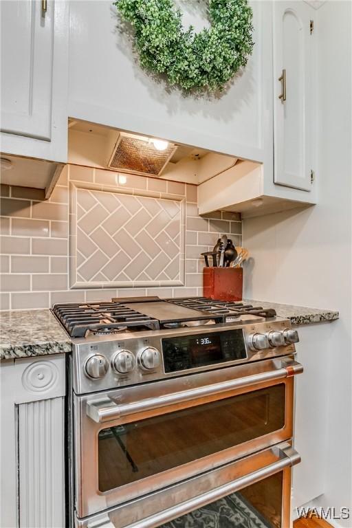 kitchen featuring light stone countertops, white cabinets, decorative backsplash, stainless steel gas stove, and custom range hood