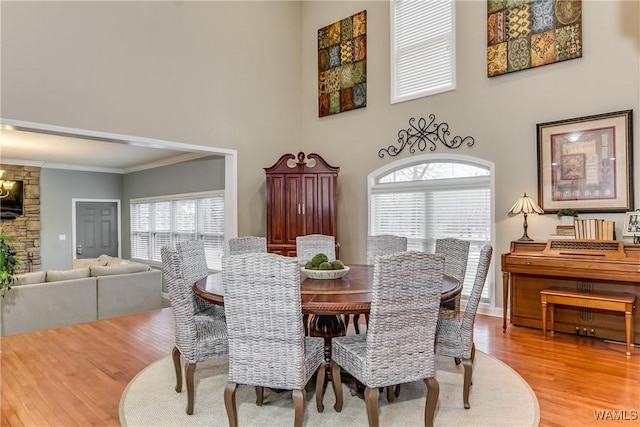 dining space featuring ornamental molding, wood finished floors, and a towering ceiling