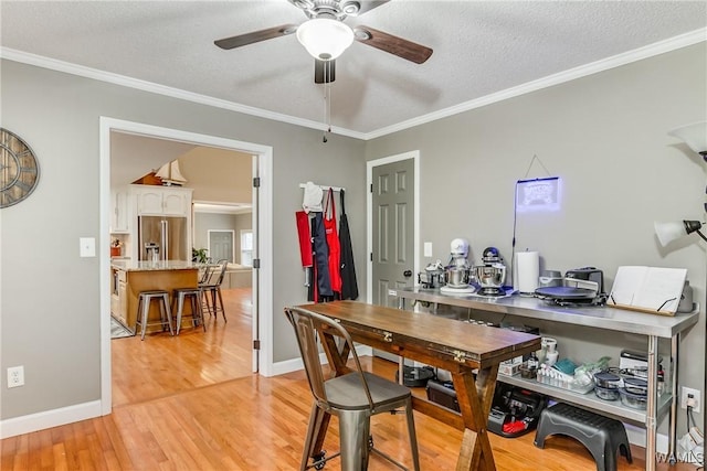 dining space with a textured ceiling, ceiling fan, baseboards, ornamental molding, and light wood-type flooring