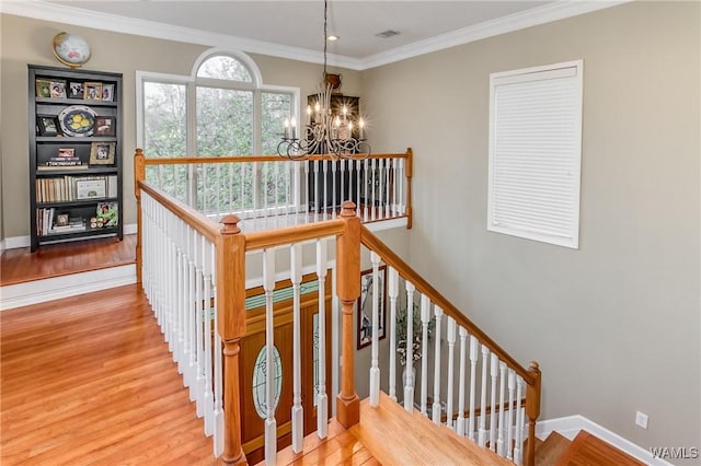 stairs featuring baseboards, a chandelier, wood finished floors, and ornamental molding