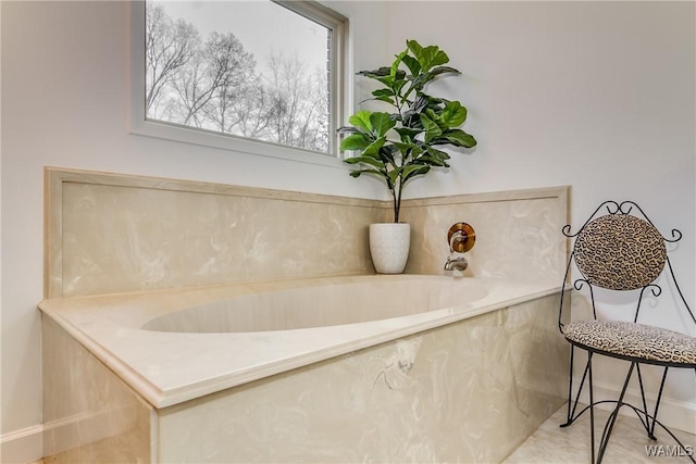 full bath with a garden tub and baseboards