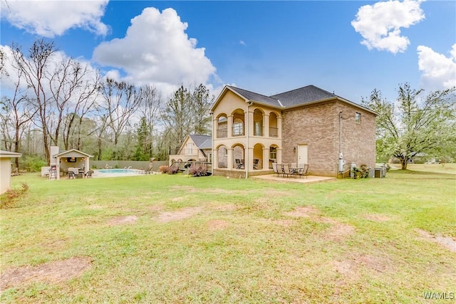 rear view of property featuring a patio, a yard, a fenced in pool, and central air condition unit