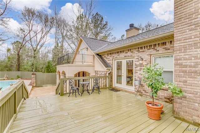 wooden terrace with french doors, fence, and a fenced in pool