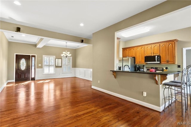 kitchen with hardwood / wood-style floors, stainless steel appliances, a notable chandelier, hanging light fixtures, and a breakfast bar