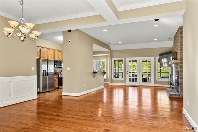 unfurnished living room with a brick fireplace, wood-type flooring, crown molding, and a chandelier