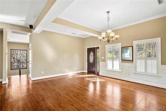 foyer with beam ceiling, wood-type flooring, crown molding, and a chandelier