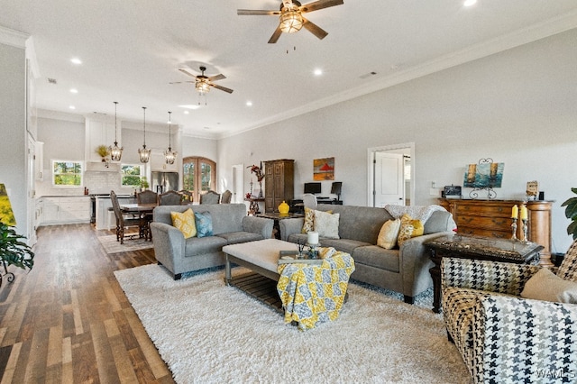 living room featuring ceiling fan, crown molding, wood-type flooring, and a towering ceiling