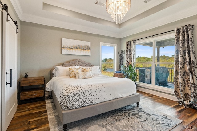 bedroom with a tray ceiling, a barn door, dark hardwood / wood-style flooring, and a notable chandelier