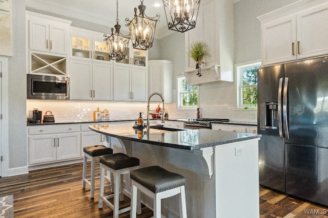 kitchen with white cabinetry, appliances with stainless steel finishes, sink, and a kitchen island with sink