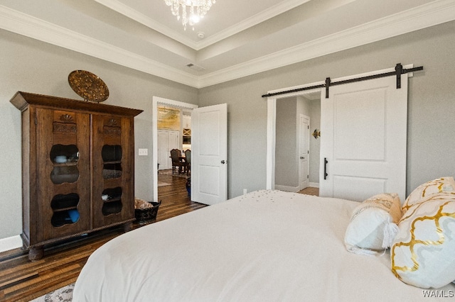 bedroom with a tray ceiling, a barn door, dark wood-type flooring, and crown molding