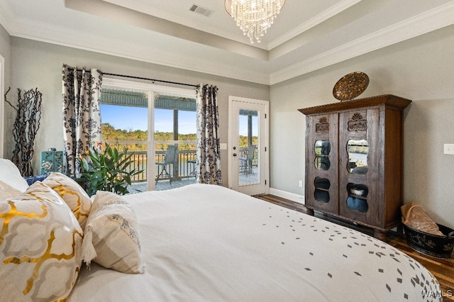 bedroom featuring wood-type flooring, access to outside, crown molding, a tray ceiling, and an inviting chandelier